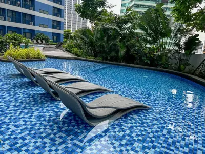 a swimming pool with chaise lounge chairs in a resort at BRAND NEW Casa Airabella with Netflix & Makati City Skyline in Manila