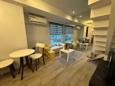 a living room with a couch and a table and chairs at Cozi Modern Loft Suite near high street BGC wifi pool in Manila