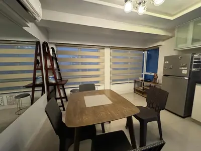 a kitchen with a table and chairs and a refrigerator at Cozi Modern Loft Suite near high street BGC wifi pool in Manila
