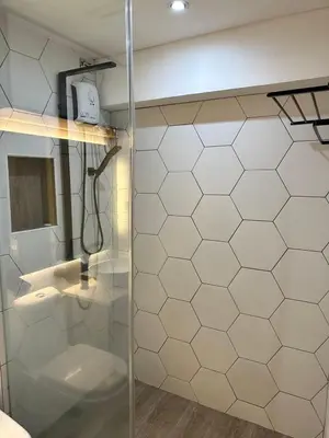 a bathroom with a glass shower with a toilet at Cozi Modern Loft Suite near high street BGC wifi pool in Manila