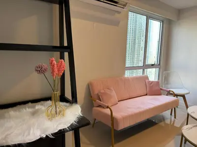 a living room with a pink couch and a vase with flowers at Cozi Modern Loft Suite near high street BGC wifi pool in Manila