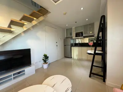 a living room with a staircase and a kitchen at Cozi Modern Loft Suite near high street BGC wifi pool in Manila