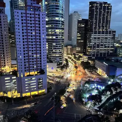 a city skyline with tall buildings and traffic at night at Air Residence in Manila