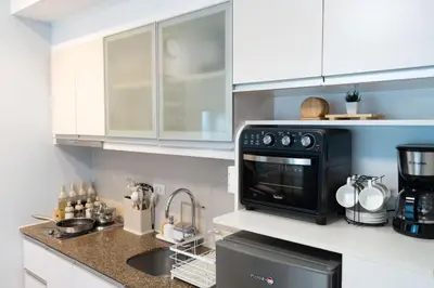 a kitchen with white cabinets and a black oven at Eastwood LeGrand 3 with Ogawa MasterdrivePlus, No Pets Allowed in Manila