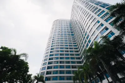 a tall building with palm trees in front of it at Eastwood LeGrand 3 with Ogawa MasterdrivePlus, No Pets Allowed in Manila