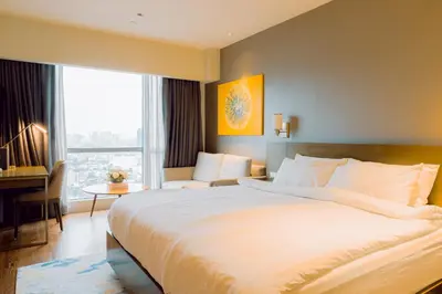 a hotel room with a large bed and a piano at The Residences at Novotel Tower in Manila