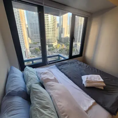 a bed in a room with two large windows at Air Residences - Pool View near Airport - 1159 in Manila