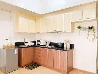 a kitchen with white cabinets and black counter tops at Chic BGC Condo by Grand Canal Mall #vlrtb27b in Manila