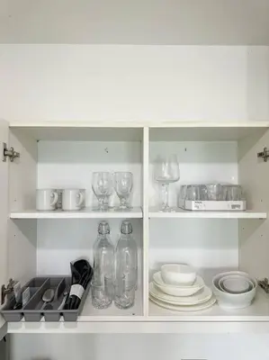 a white cabinet with glasses and plates and wine glasses at Casa Alivia at Azure UrbanResort in Manila