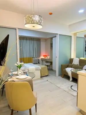 a living room with a bed and a living room with a table at Casa Alivia at Azure UrbanResort in Manila