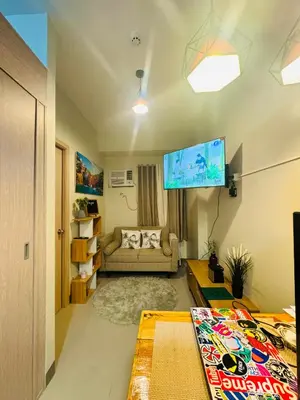 a living room with a couch and a flat screen tv at The J-MA UltiEscape Charm Residences Condo in Manila