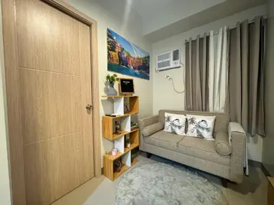 a small living room with a couch and a door at The J-MA UltiEscape Charm Residences Condo in Manila