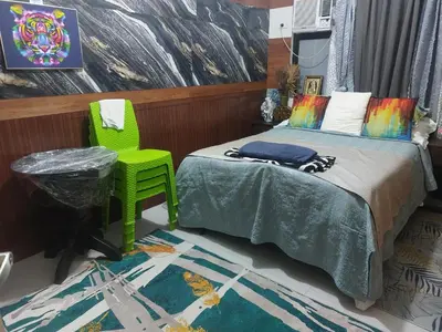 a bedroom with a bed and a green chair at Florida sun condo near lyceum in General Trias
