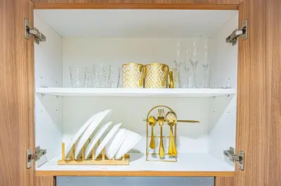 a cabinet filled with shelves with gold and silverware at MOA Staycation Haven Cozy 1BR Retreat with Balcony at Shore 3 in Manila