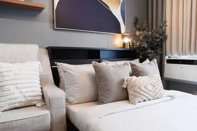a bedroom with a bed and a couch with pillows at Newly Renovated Pasig Studio with Pool and Fiber Wi-Fi in Manila
