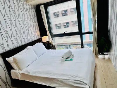 a bedroom with a white bed and a window at Comfy 1BR Across International Airport in Manila