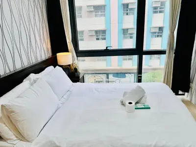 a white bed with a stuffed elephant on it at Comfy 1BR Across International Airport in Manila
