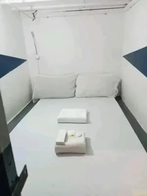 a small room with a white bed with two pillows at RDC - Mariveles Transient Capsule in Manila