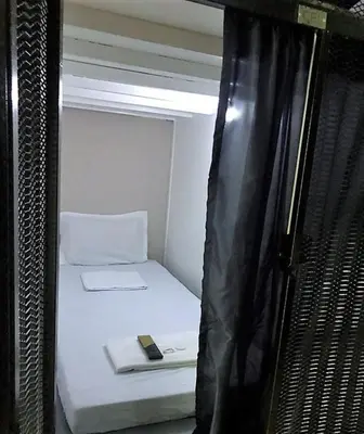 a small room with a bed with a cell phone on it at RDC - Mariveles Transient Capsule in Manila