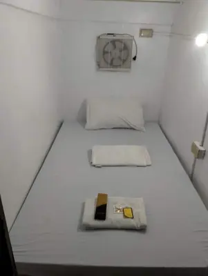 a small bedroom with two beds and a fan at RDC - Mariveles Transient Capsule in Manila