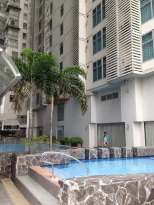 a swimming pool in front of a building with palm trees at Studio deluxe cozy staycation Antel Spa Residences in Manila