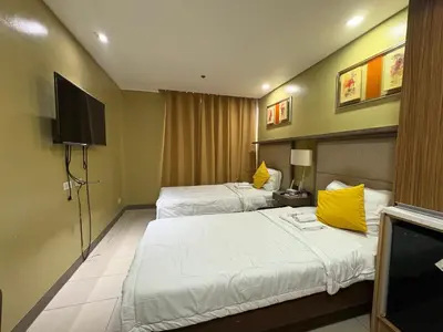 a hotel room with two beds and a flat screen tv at Studio deluxe cozy staycation Antel Spa Residences in Manila