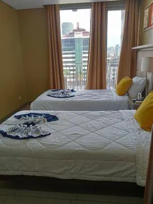 two beds in a hotel room with a window at Studio deluxe cozy staycation Antel Spa Residences in Manila