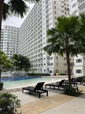 a large building with a swimming pool with benches and a palm tree at shore staycation 559 in Manila