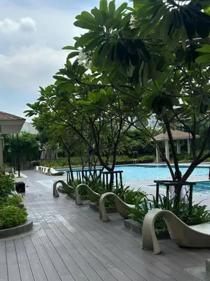 a row of benches next to a pool with trees at 1-BR Condo with Pool & Skyline Views in Pasig in Manila