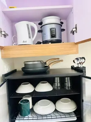 a shelf with dishes and pots and pans in a kitchen at 1-BR Condo with Pool & Skyline Views in Pasig in Manila