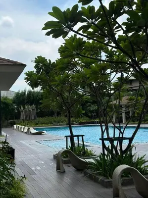 a swimming pool with chairs and trees next to a building at 1-BR Condo with Pool & Skyline Views in Pasig in Manila