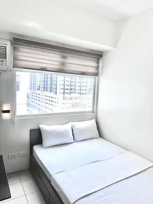 a small bedroom with a bed and a window at Hotel in Mandaluyong in Manila