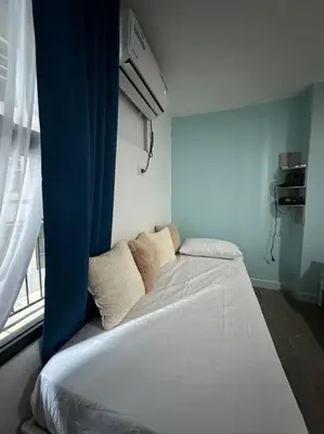 a bed sitting in a room with a window at Studio w projector Wifi Netflix and pool access in ADB Tower Ortigas CBD in Manila