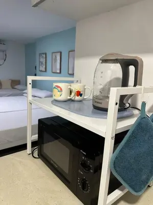 a room with a bed and a microwave on a shelf at Studio w projector Wifi Netflix and pool access in ADB Tower Ortigas CBD in Manila