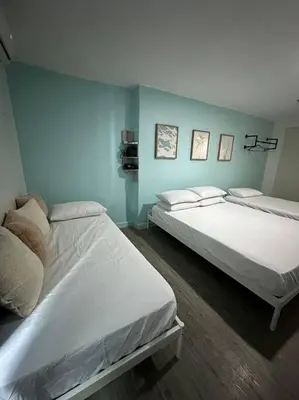 two beds in a room with blue walls at Studio w projector Wifi Netflix and pool access in ADB Tower Ortigas CBD in Manila