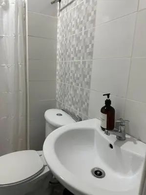 a white bathroom with a toilet and a sink at Studio w projector Wifi Netflix and pool access in ADB Tower Ortigas CBD in Manila