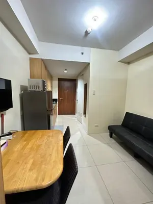 a living room with a wooden table and a couch at shell staycation in Manila