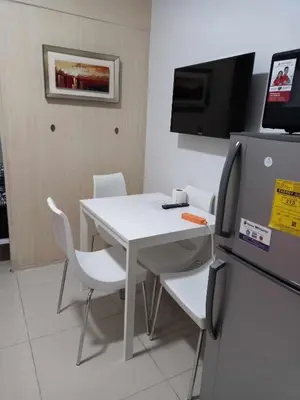 a room with a white table and chairs and a tv at Sea res moa by Elsie D in Manila