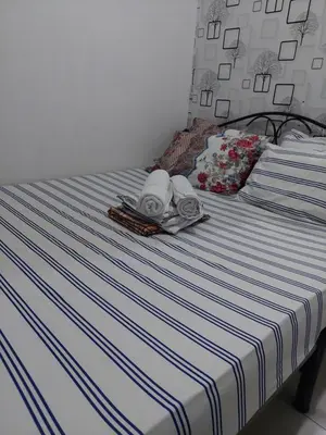 a bed with a blue and white striped sheets at Sea res moa by Elsie D in Manila
