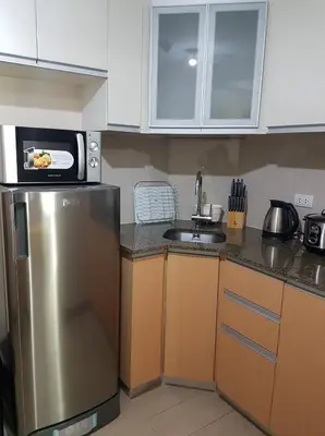 a kitchen with a stainless steel refrigerator and a microwave at Newport City Condos in Manila