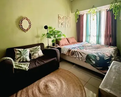 a bedroom with a bed and a couch and a window at Tropical Haven in Makati CBD in Manila
