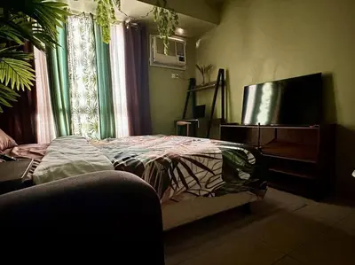 a bedroom with a bed and a flat screen tv at Tropical Haven in Makati CBD in Manila