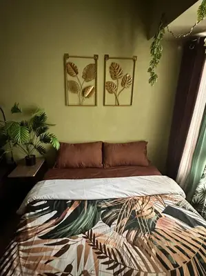 a bed in a bedroom with two pictures on the wall at Tropical Haven in Makati CBD in Manila