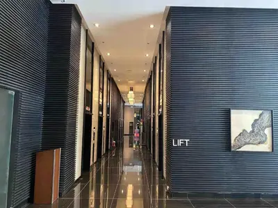 a hallway of a building with a woman walking down it at Air Residences - High Floor City View near Airport - 5759 in Manila