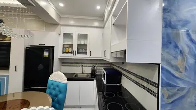 a kitchen with white cabinets and a table at SMDC Coast Residences in Manila