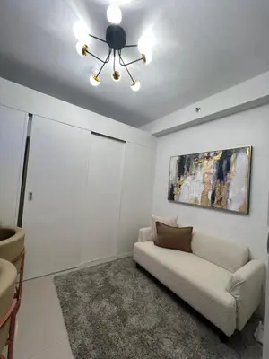 a living room with a couch and a painting on the wall at Shore 2 Tower 3 in Manila