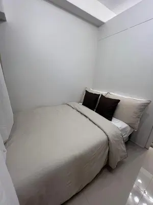 a white bedroom with a large bed with black pillows at Shore 2 Tower 3 in Manila