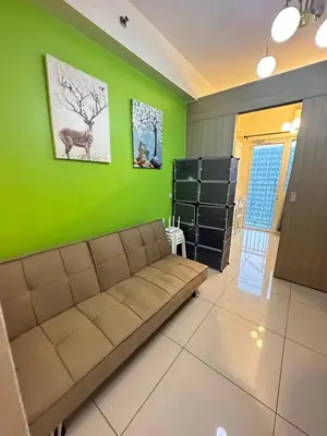 a living room with a couch and a green wall at Lanz staycation breeze residences in Manila