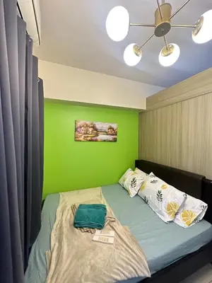 a green bedroom with a bed with a green wall at Lanz staycation breeze residences in Manila