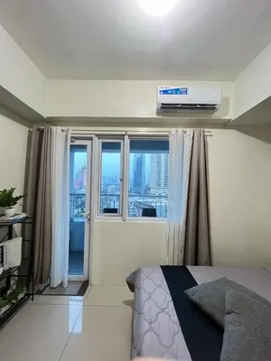 a bedroom with a bed and a window with a air conditioner at SM Jazz Residence Tower B in Manila